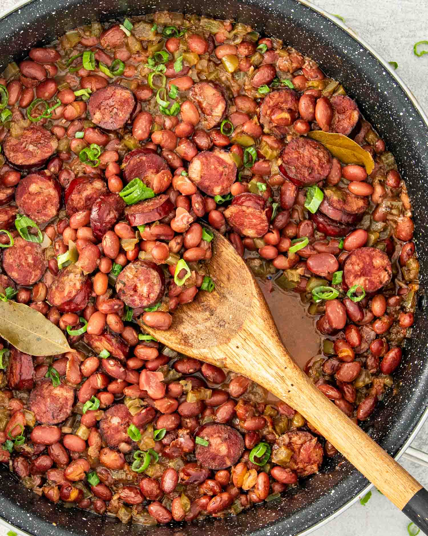 red beans in a skillet with a wooden spoon inside.
