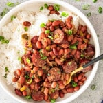 red beans and rice in a white bowl garnished with green onions.