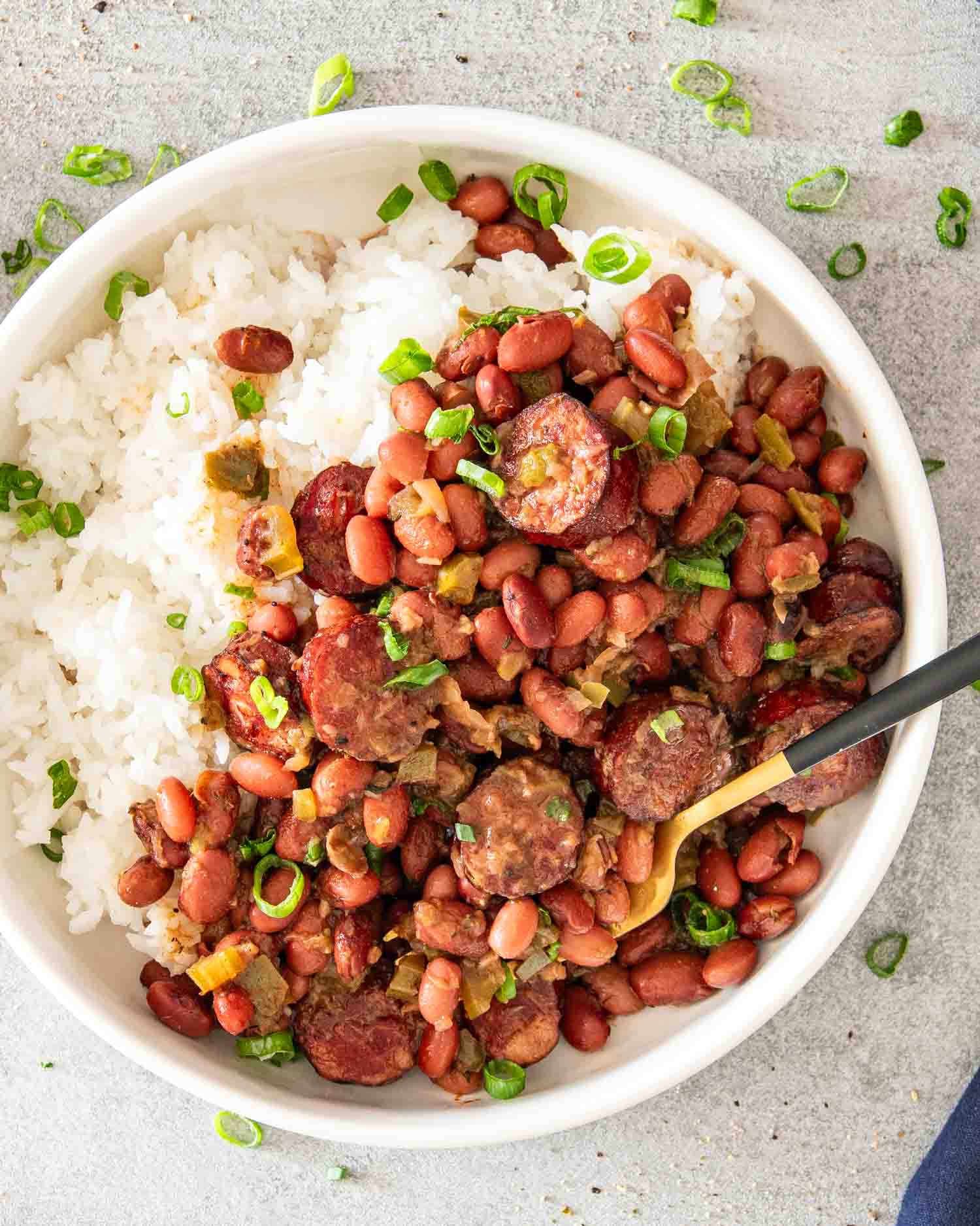 red beans and rice in a white bowl garnished with green onions.