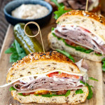 a roast beef sandwich cut in half on a cutting board.