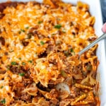 a sloppy joe casserole in a white casserole dish with a serving spoon inside.