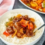 sweet and sour pork on a bed of rice in a white bowl.