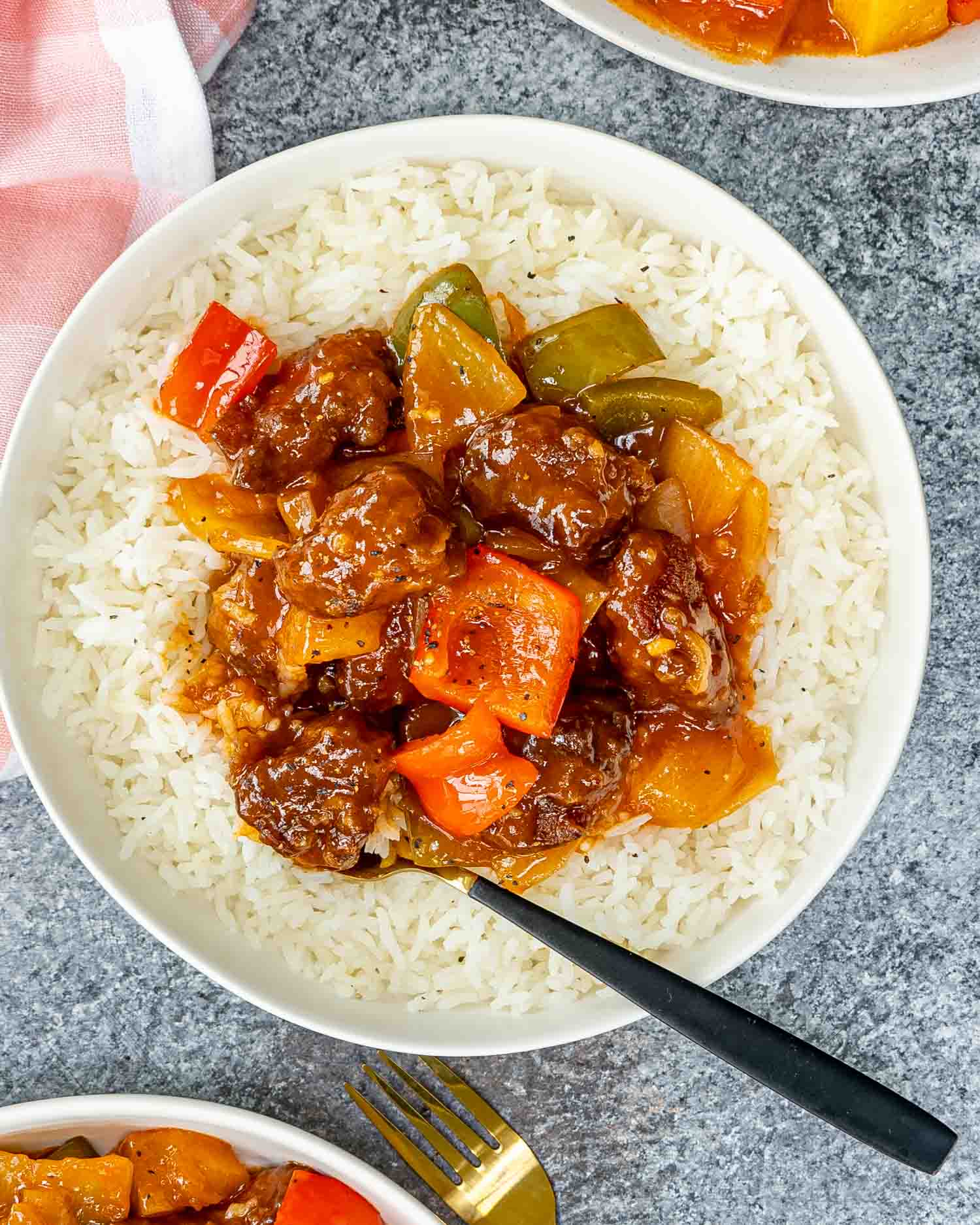 sweet and sour pork on a bed of rice in a white bowl.
