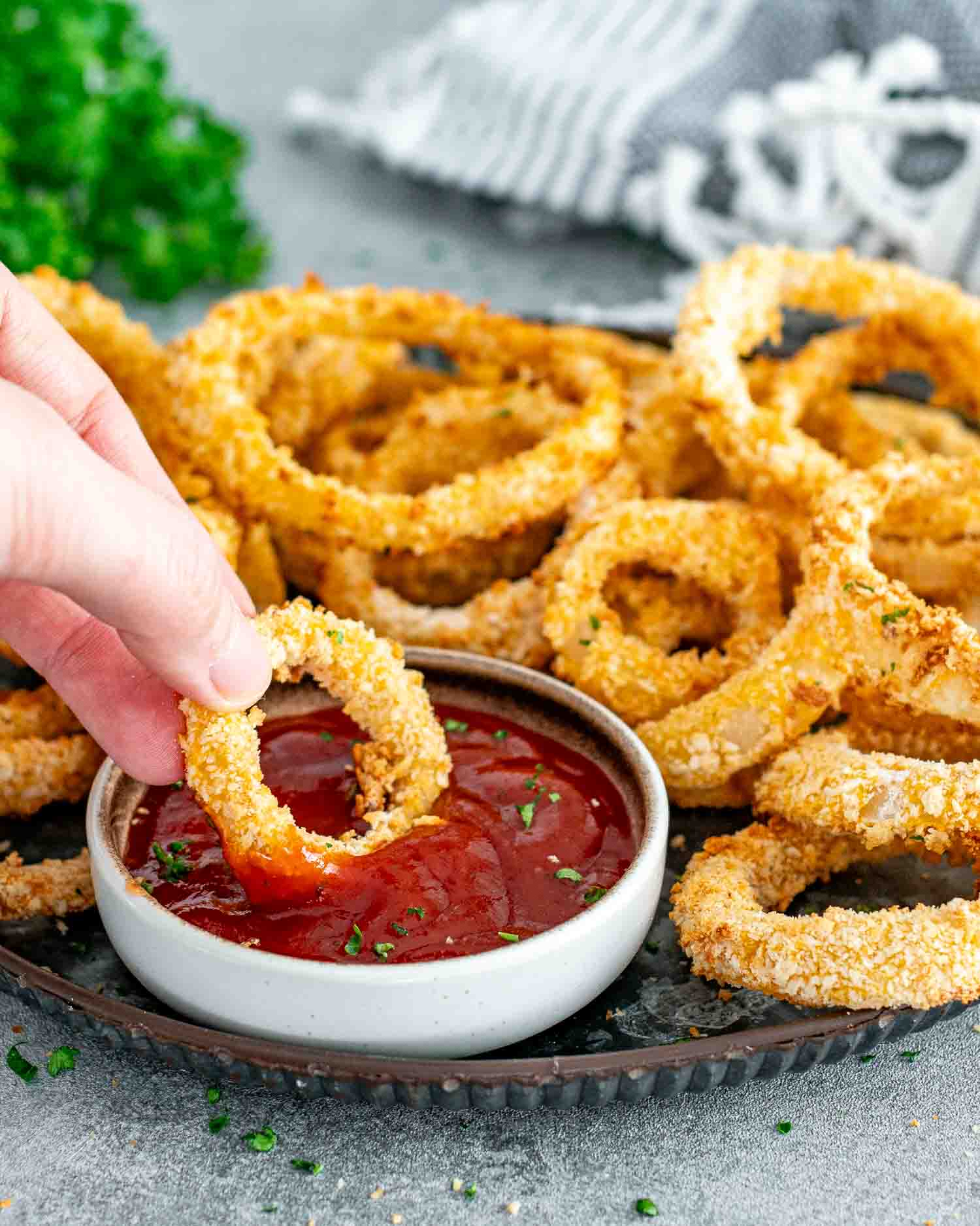 freshly made onion rings in the air fryer on a metal plate with ketchup.
