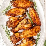 freshly made air fryer turkey wings on a white platter garnished with rosemary.