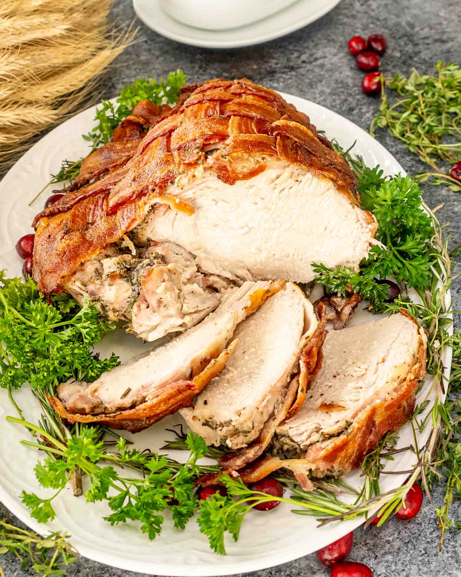 bacon wrapped turkey breast sliced on a turkey platter.