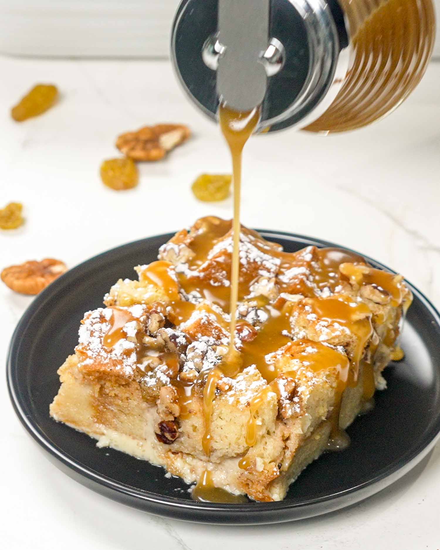 pouring caramel sauce over a slice of bread pudding.