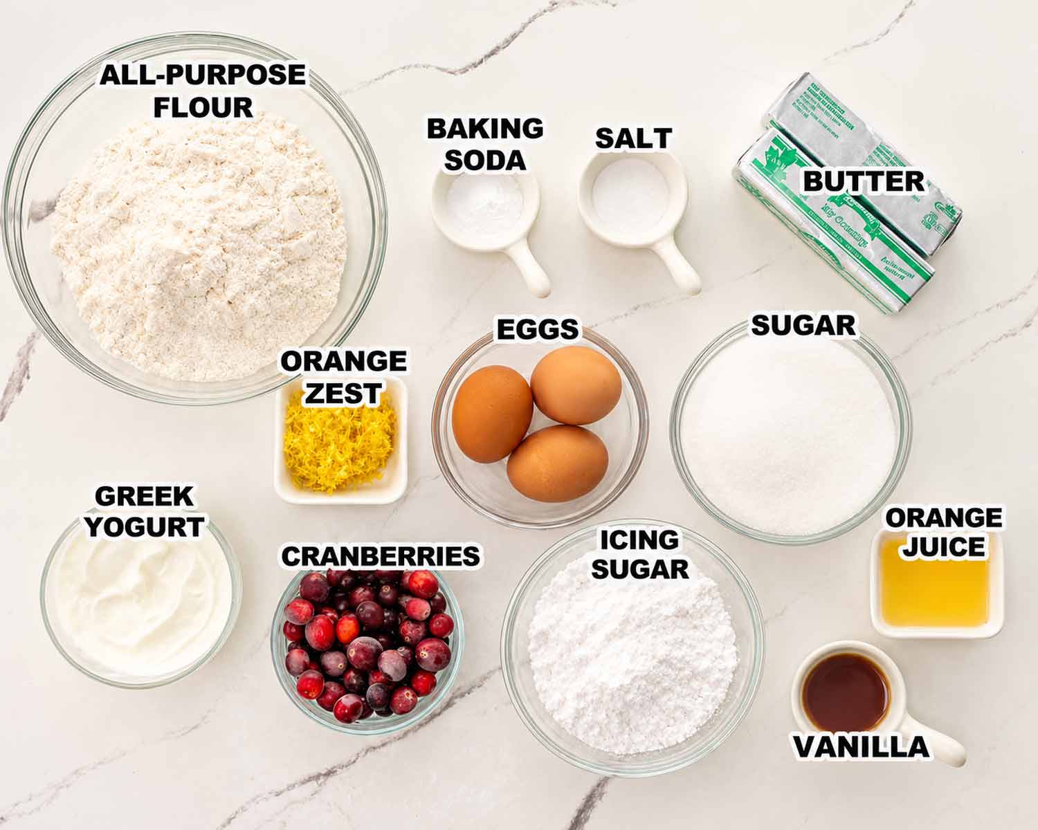 Overhead display of labeled cranberry coffee cake ingredients, including cranberries, orange zest, Greek yogurt, and glaze ingredients.