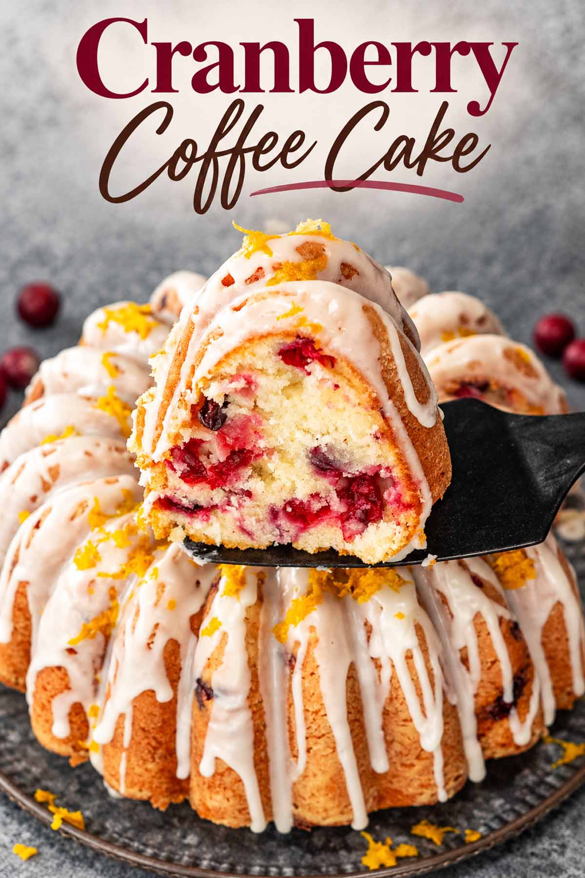 Cranberry coffee cake with orange glaze and zest, featuring a berry-filled slice lifted above the Bundt cake.