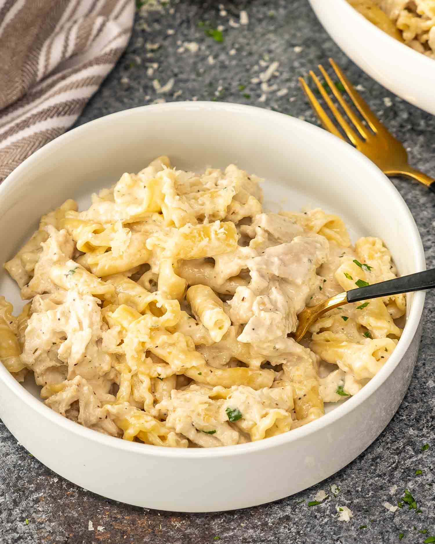 a serving of chicken alfredo in a white bowl.