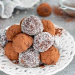 a few chocolate truffles on a plate, some with cocoa powder and some with coconut.