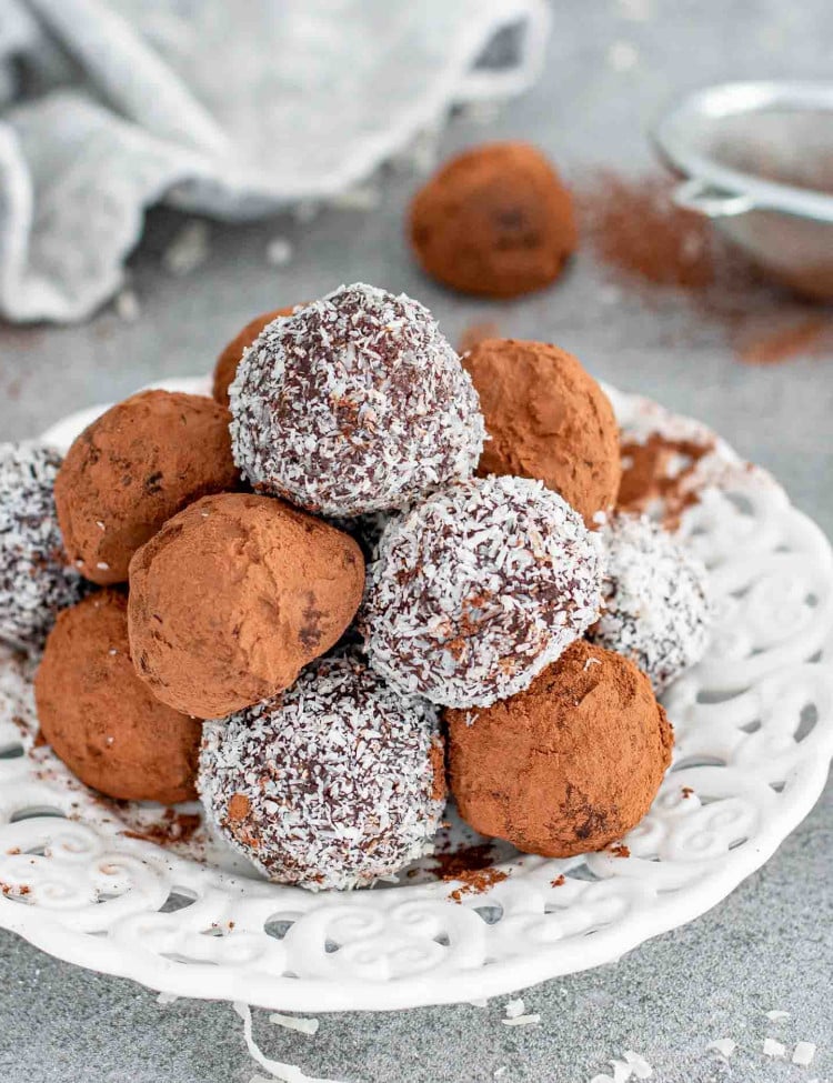 a few chocolate truffles on a plate, some with cocoa powder and some with coconut.