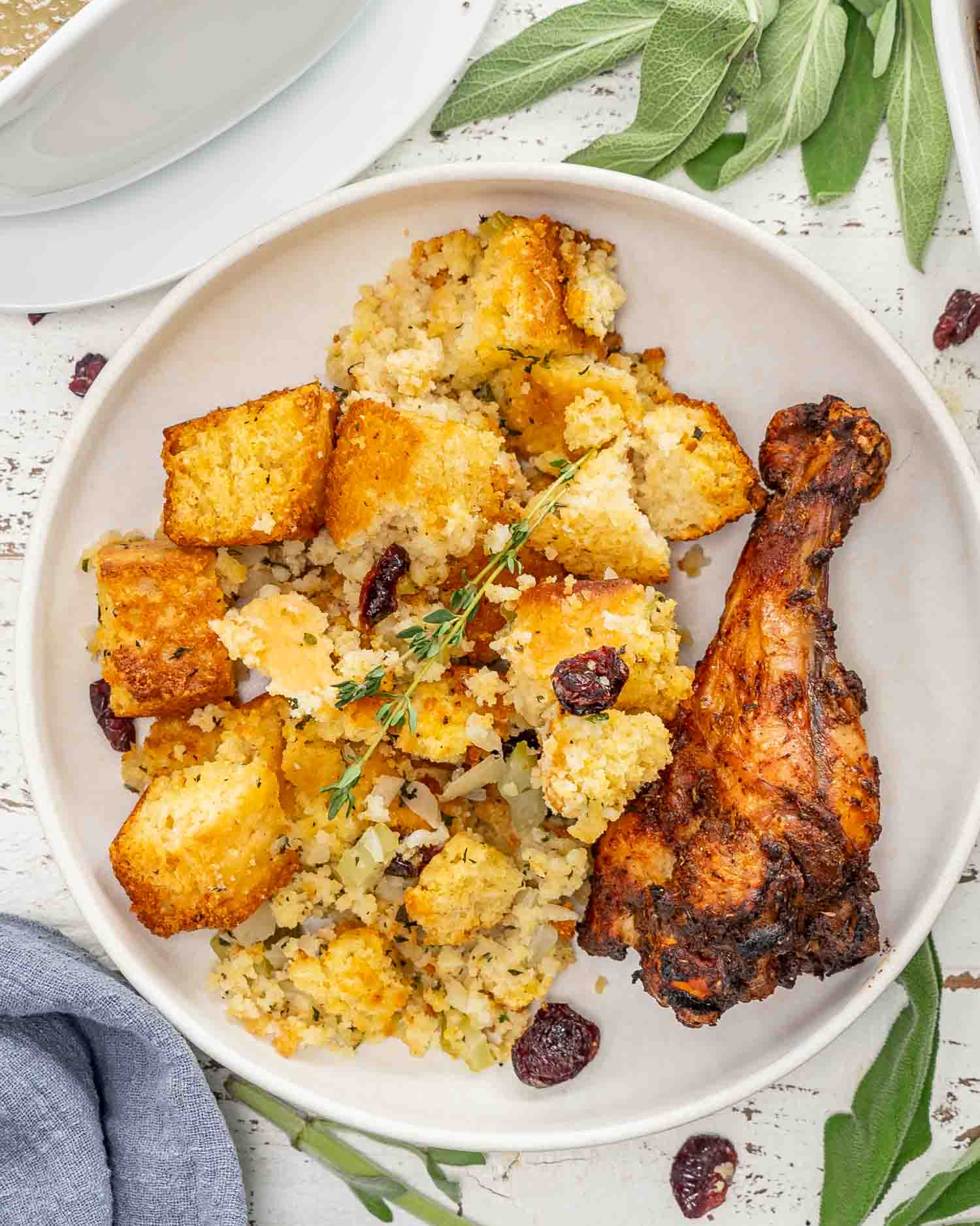 cornbread stuffing in a white dish with a turkey thigh.