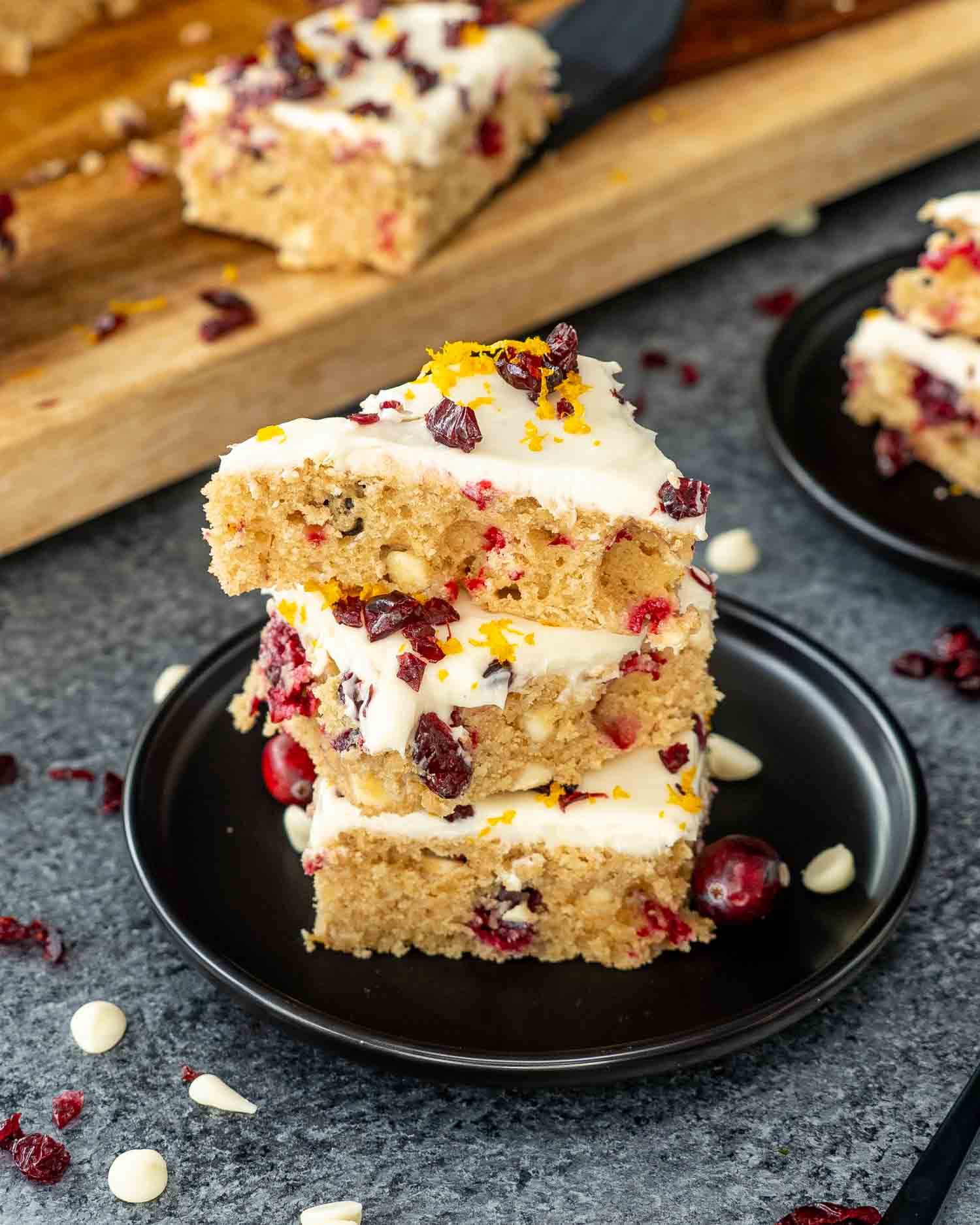 a stack of 3 cranberry bars on a black dessert plate.