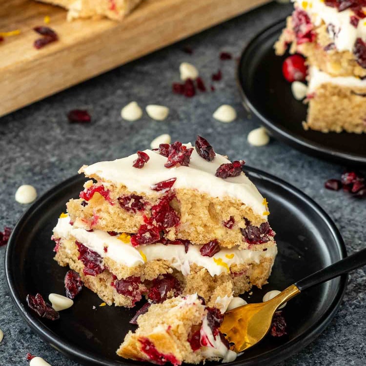 a stack of 3 cranberry bars on a black dessert plate.