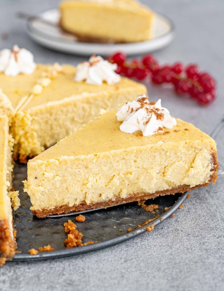 a beautiful eggnog cheesecake topped with whipped cream with a slice being taken out.