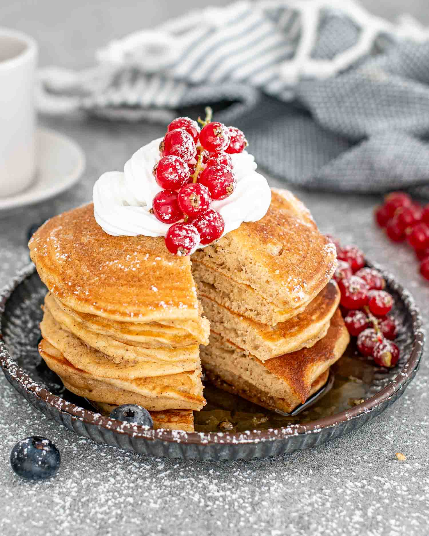 a stack of eggnog pancakes dusted with powdered sugar and a dollop of whipped cream.