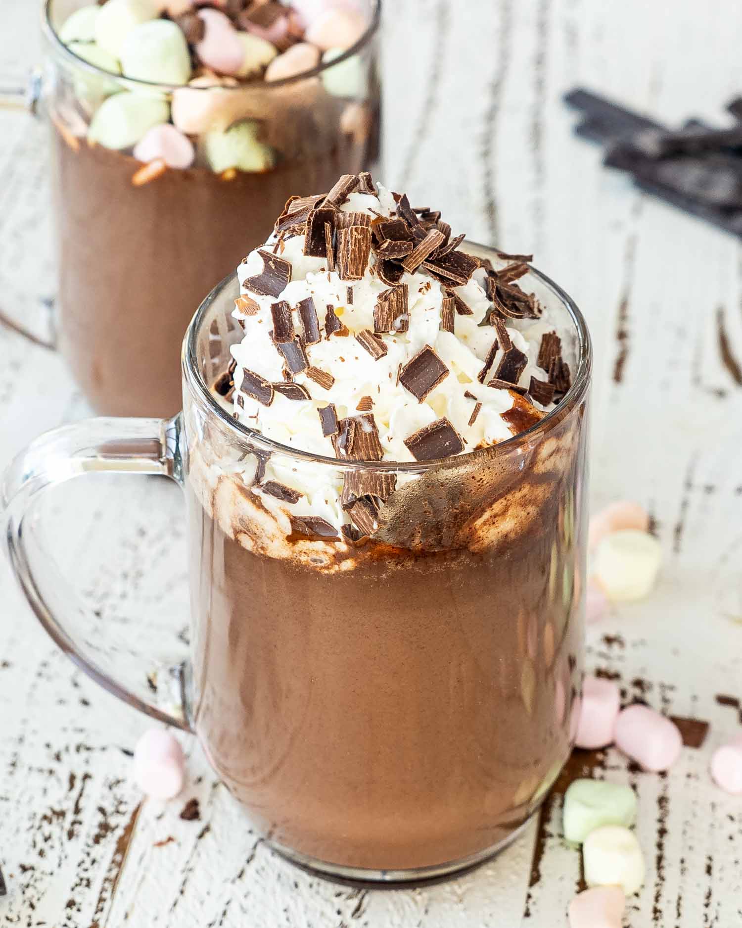a hot chocolate in a mug topped with whipped cream and chocolate shavings.