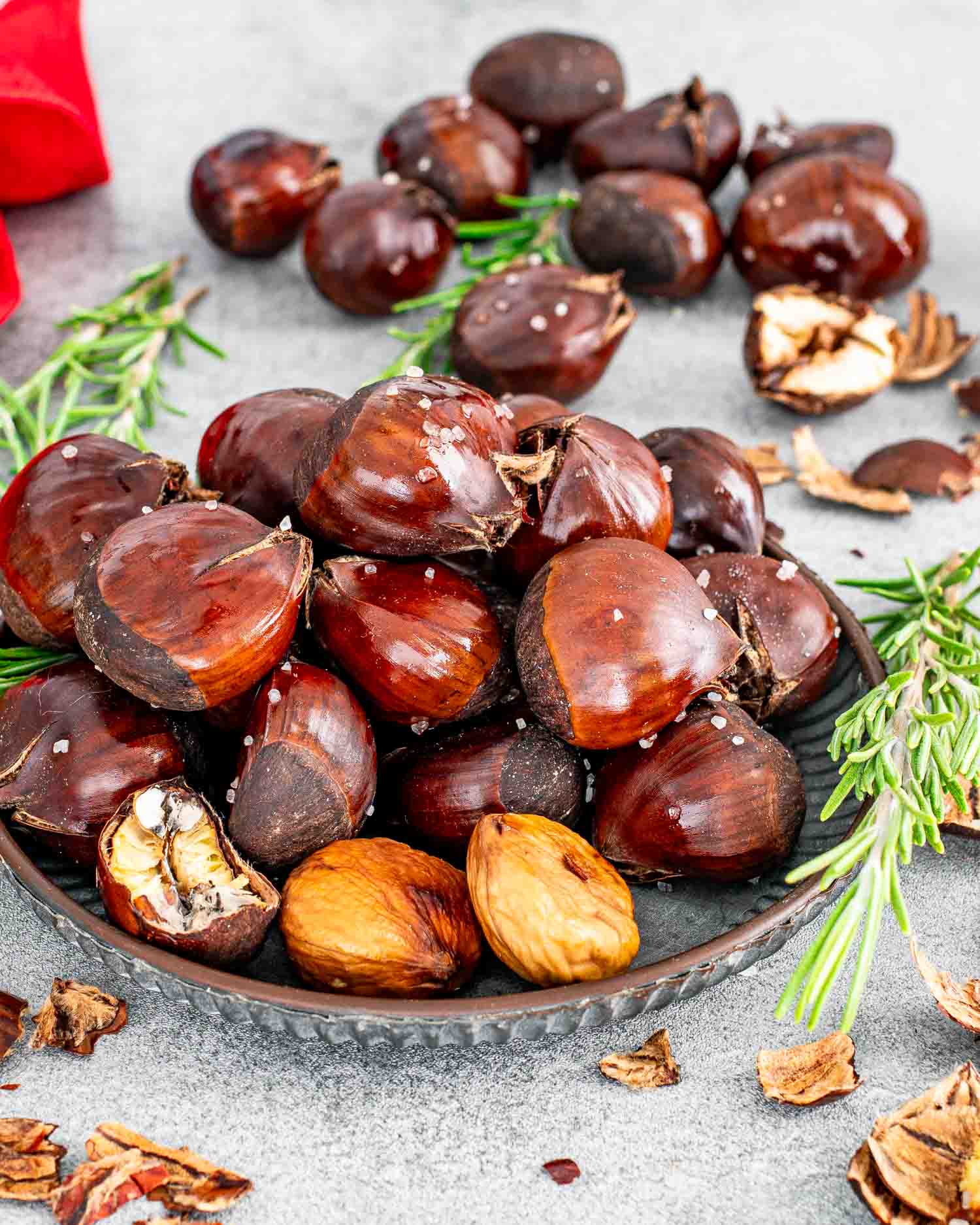 roasted chestnuts on a plate along some fresh rosemary.