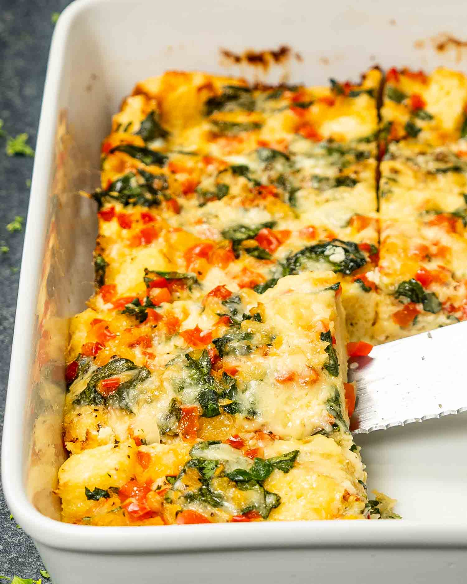 freshly baked strata cut into pieces in a white casserole dish.