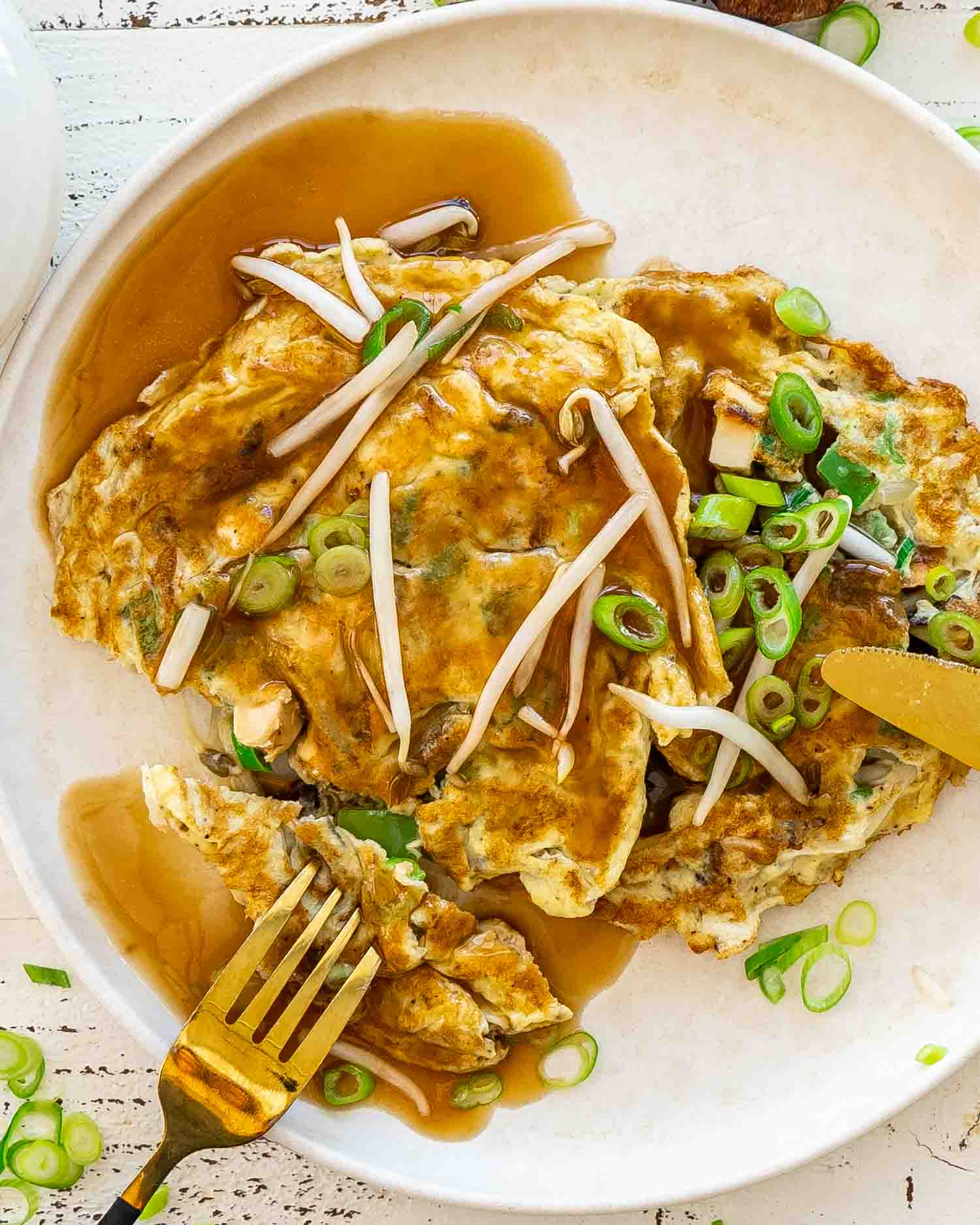 egg foo young on a white plate with sauce.