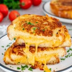 a grilled cheese sandwich cut in half and stacked on a white plate.