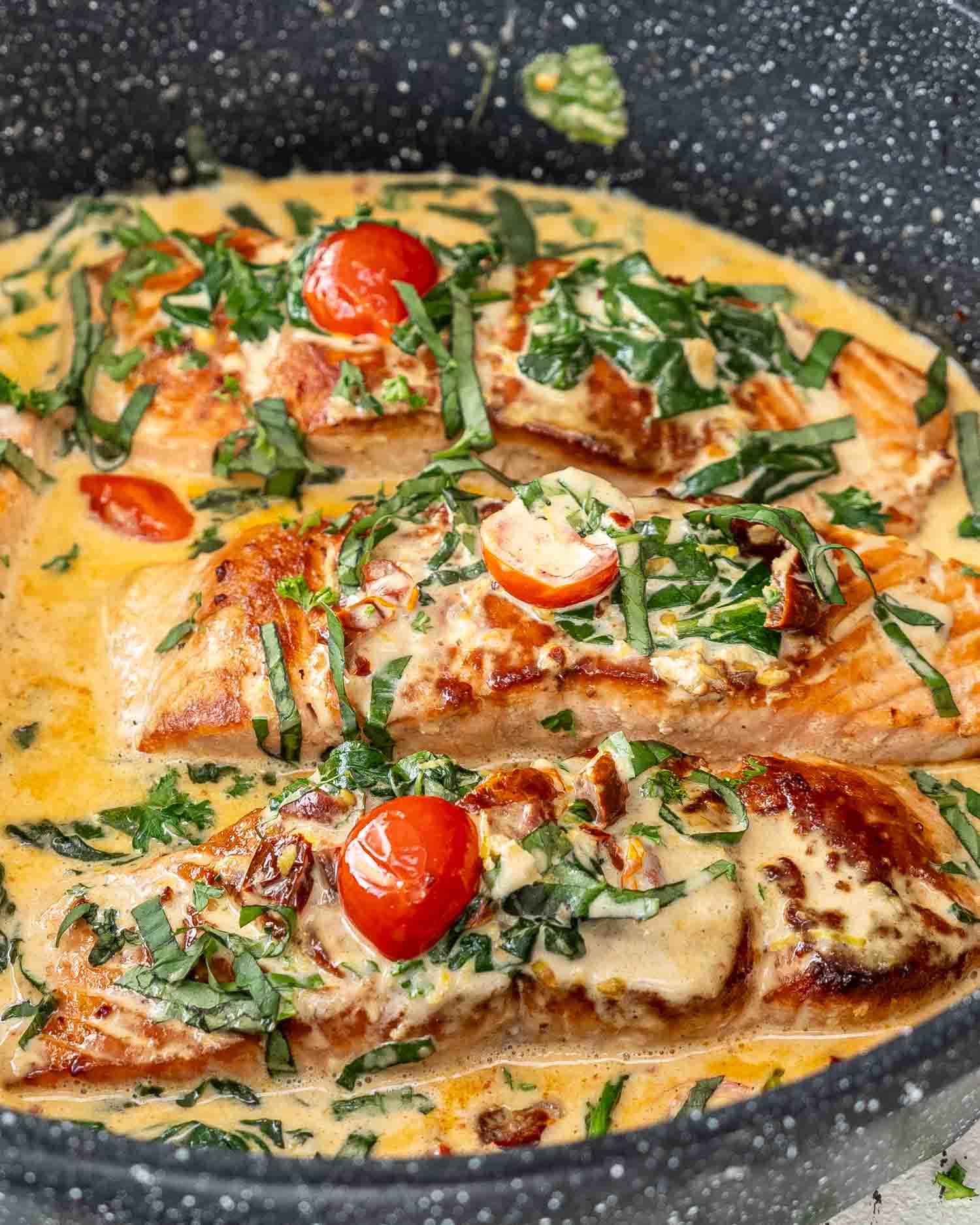 freshly made tuscan salmon in a skillet garnished with basil.