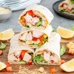 a couple chicken caesar wraps cut in half on a cutting board.