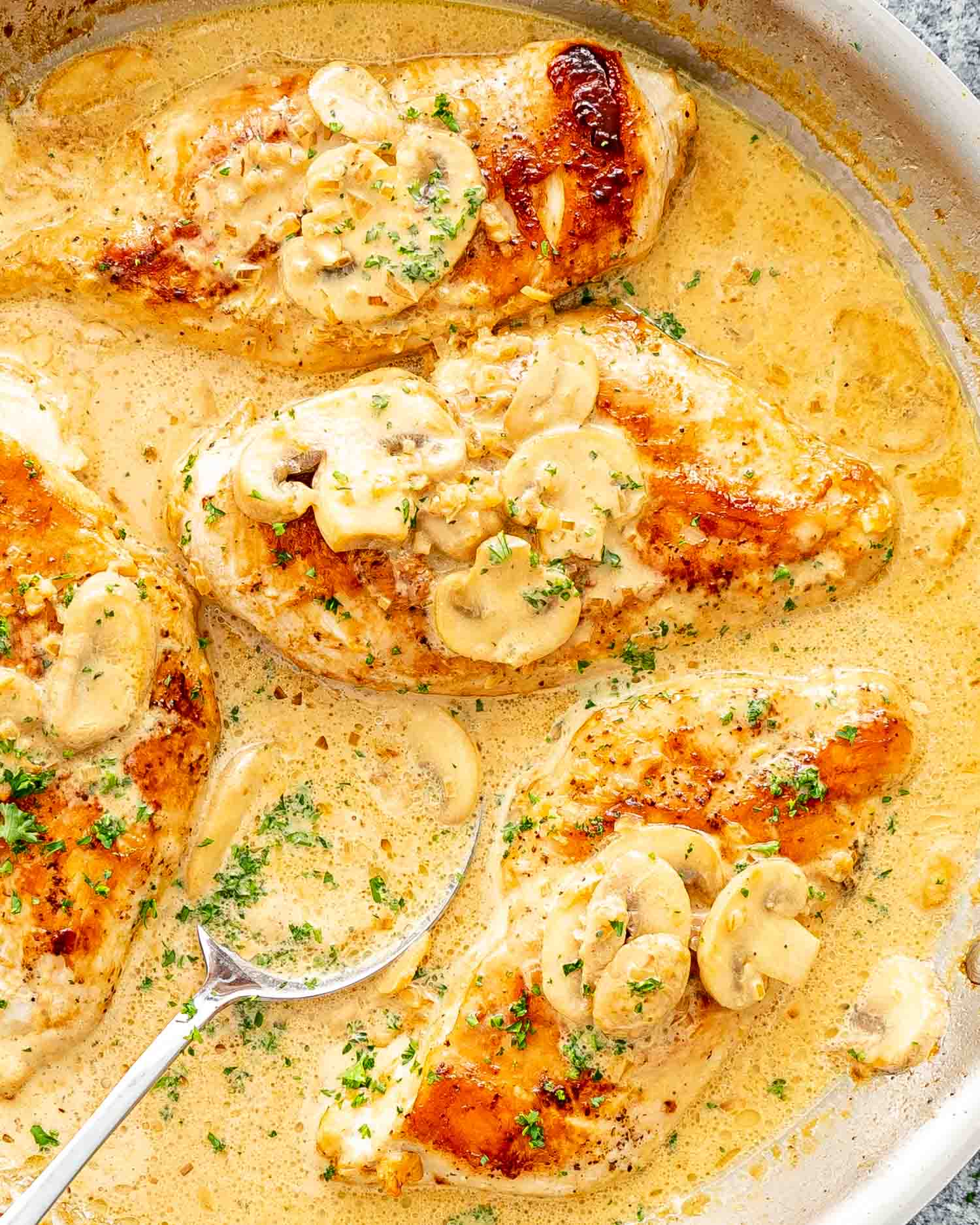 Golden Chicken Diane with mushrooms in a creamy sauce, sprinkled with parsley in a skillet.