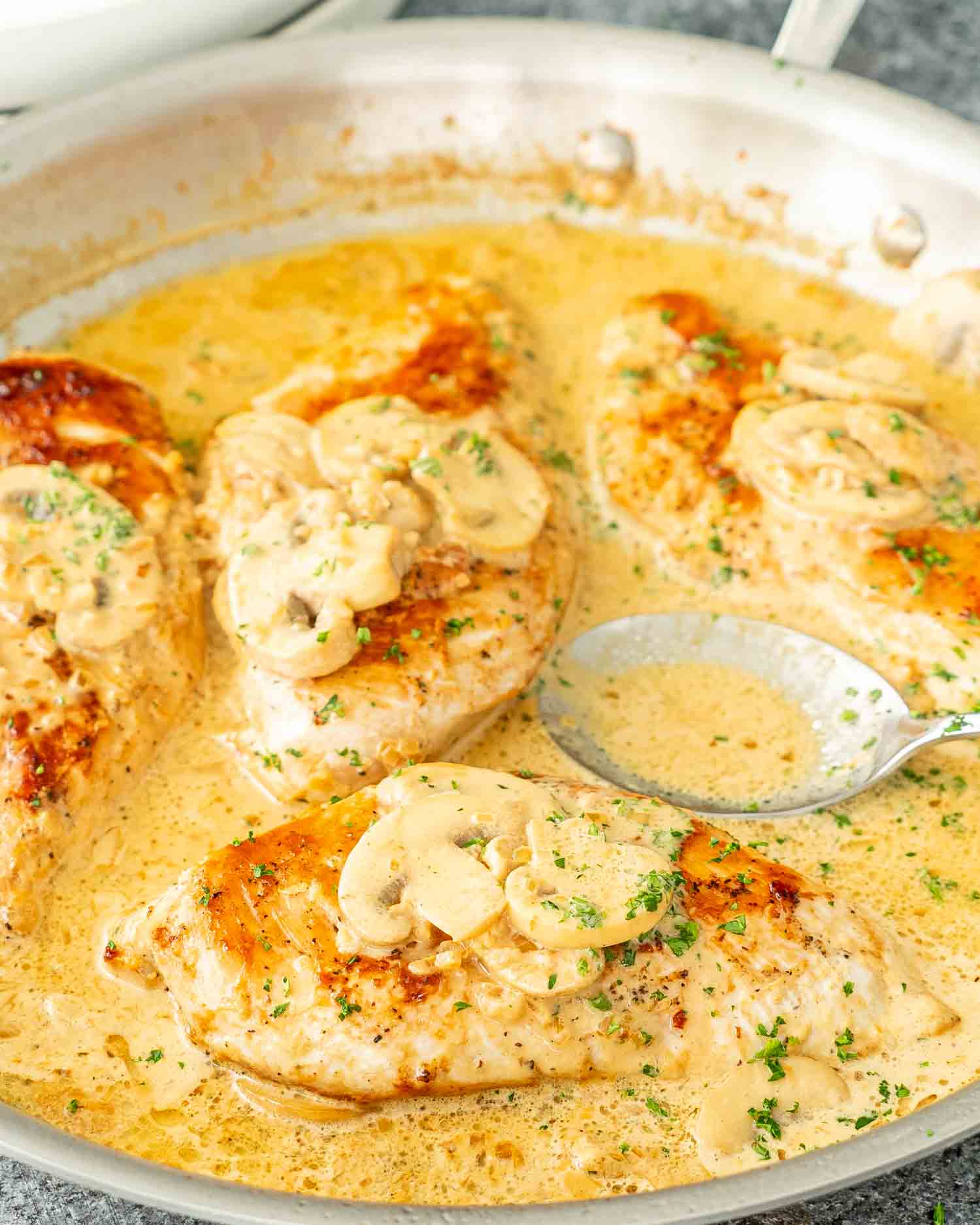 Golden Chicken Diane with mushrooms in a creamy sauce, sprinkled with parsley in a skillet.