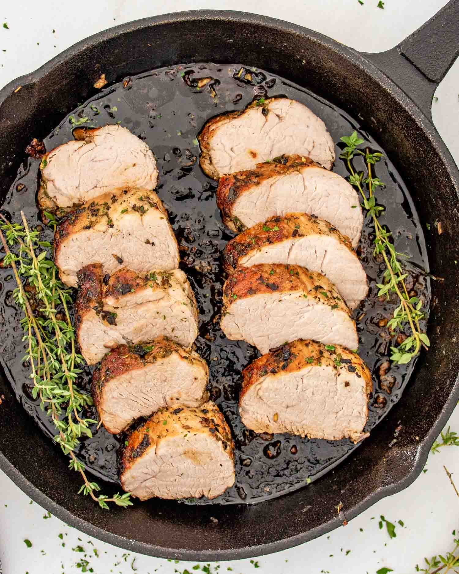 a cast iron skillet with sliced herb crusted pork tenderloin.