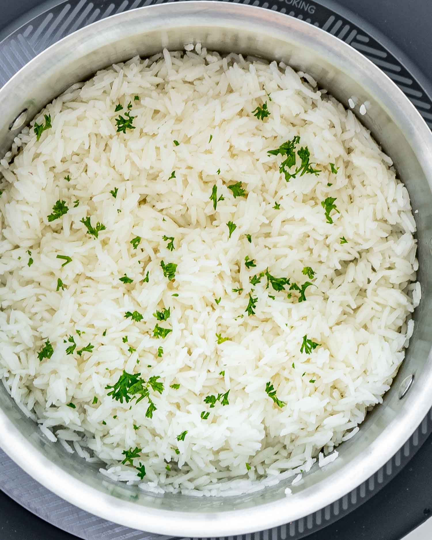 perfectly cooked jasmine rice in a pot garnished with parsley.