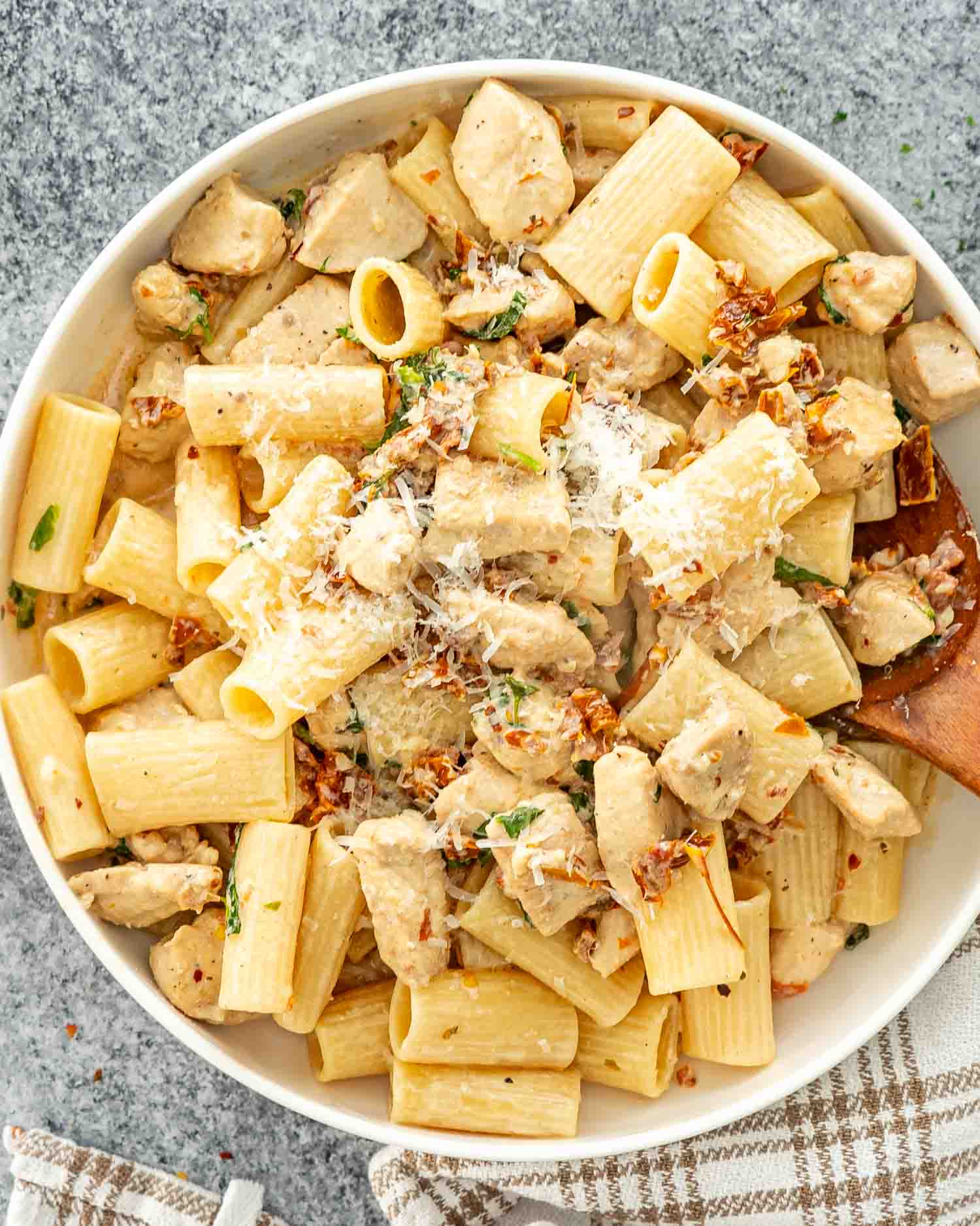 a big white bowl loaded with marry me chicken pasta and garnished with parmesan cheese.