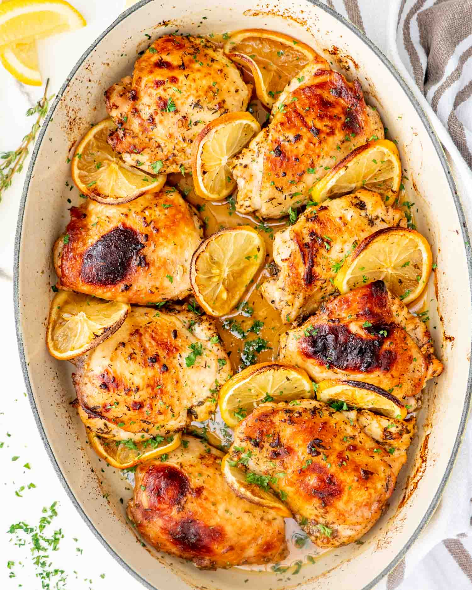 baked lemon chicken thighs in a oval baking dish garnished with parsley.