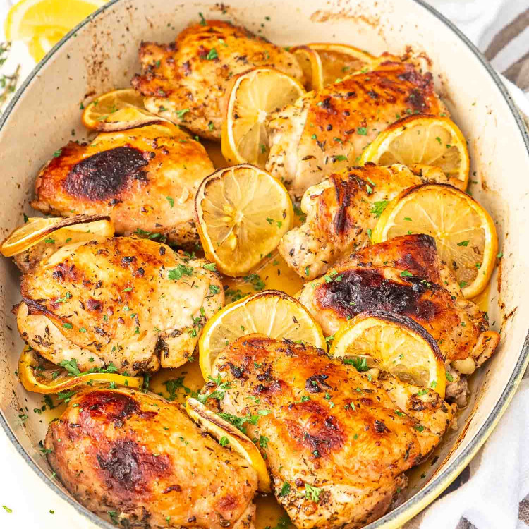 baked lemon chicken thighs in a oval baking dish garnished with parsley.