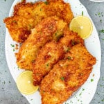 a few chicken cutlets on a white platter.