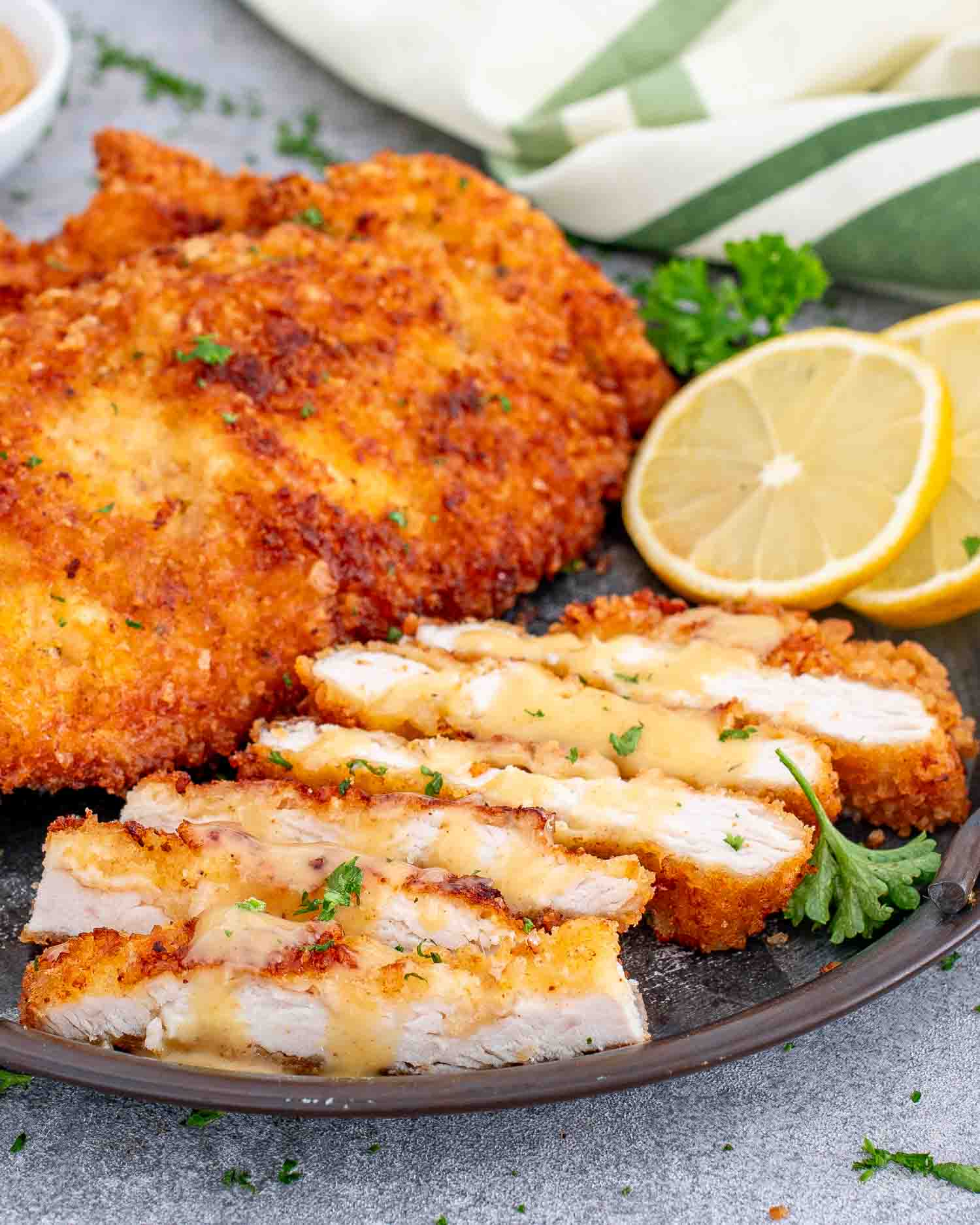 a sliced up chicken cutlet on a plate with honey mustard sauce. 
