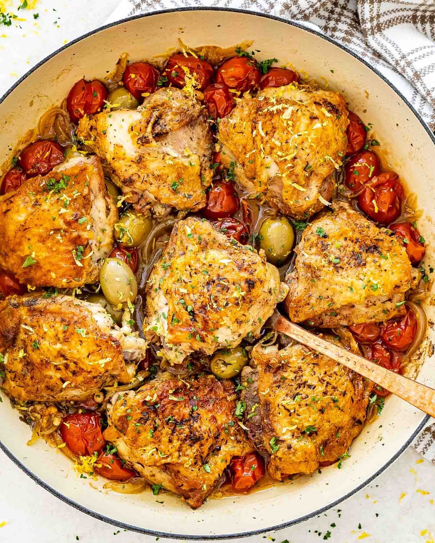 chicken provencal in a dutch oven garnished with parsley and lemon zest.