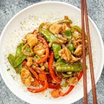 chop suey over a bed of rice in a white plate.