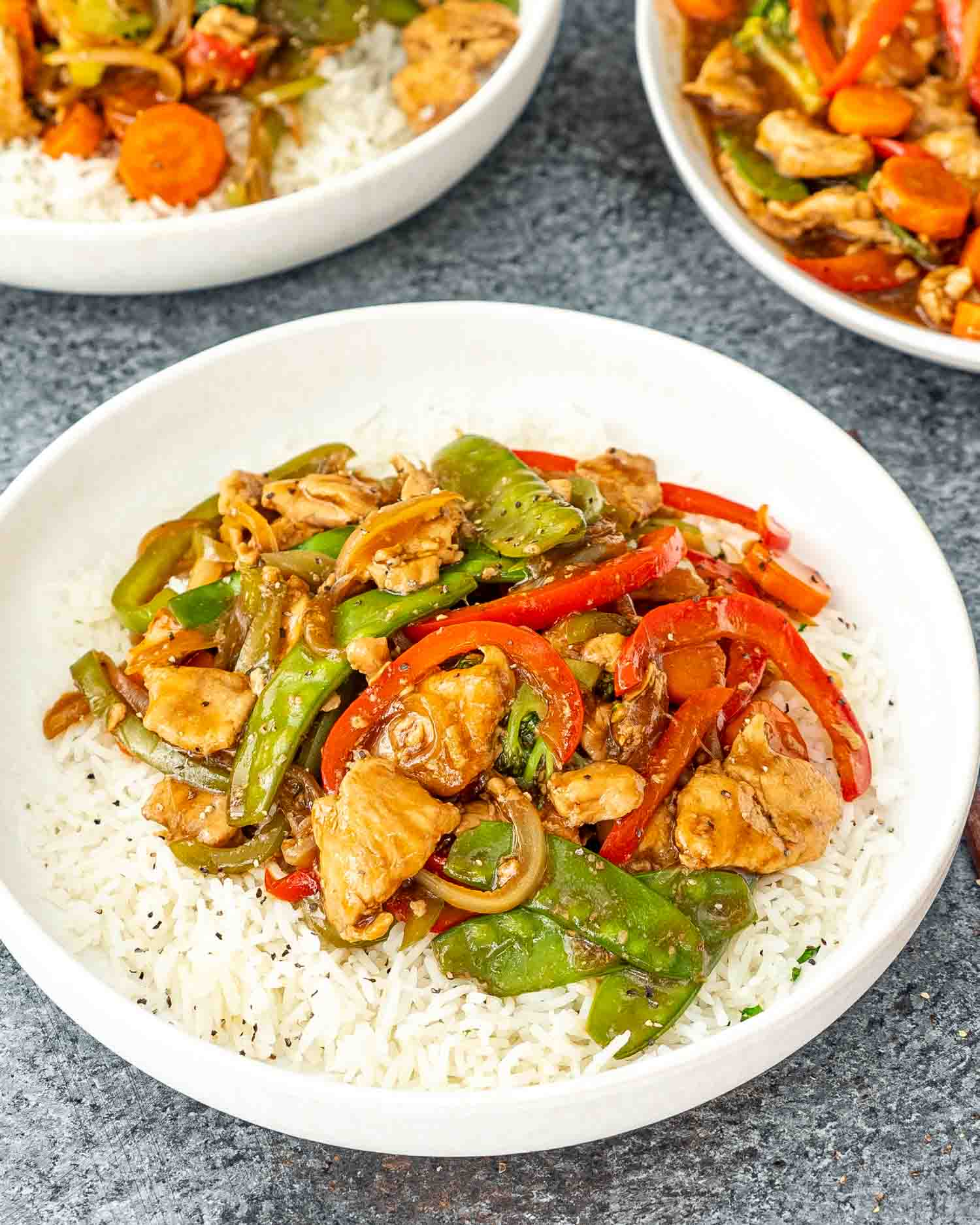 chop suey over a bed of rice in a white plate.