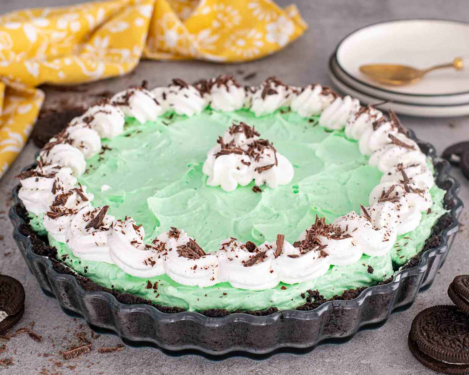a grasshopper pie in a tart shell topped with whipped cream and oreo cookie crumble.