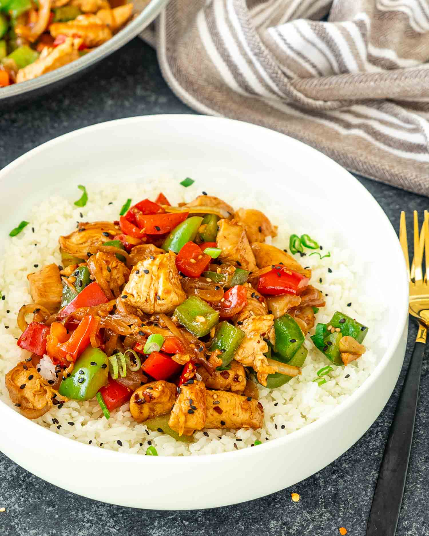 a serving of pepper chicken stir fry over a bed of jasmine rice.