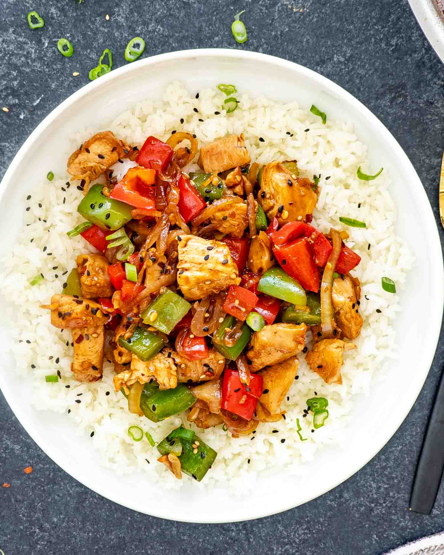 a serving of pepper chicken stir fry over a bed of jasmine rice.