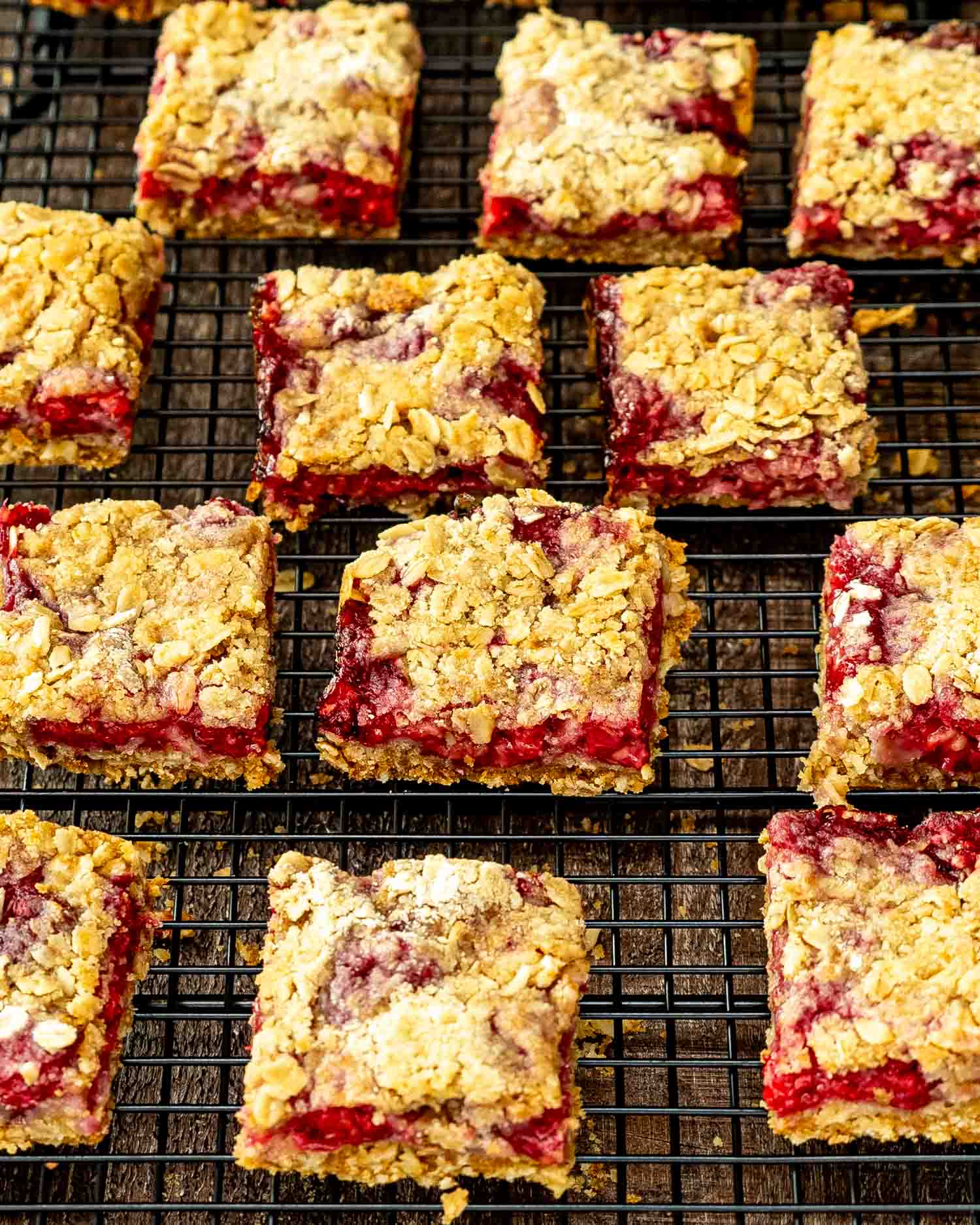 freshly baked raspberry oatmeal crumble bars on a black cooling rack.