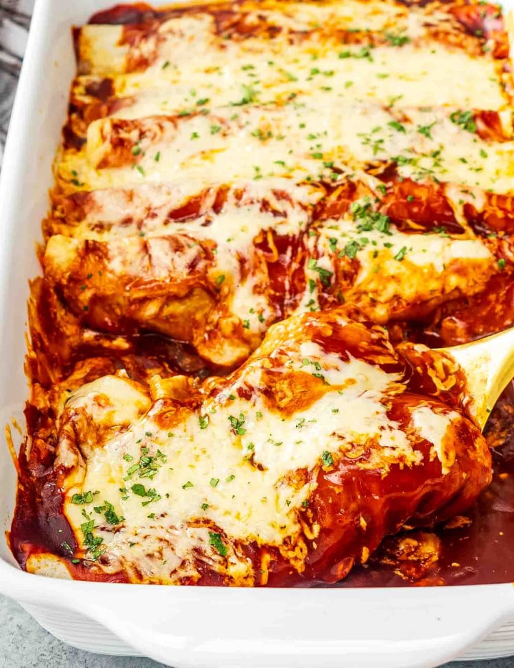 freshly baked cheesy beef enchiladas in a white casserole dish garnished with fresh cilantro.