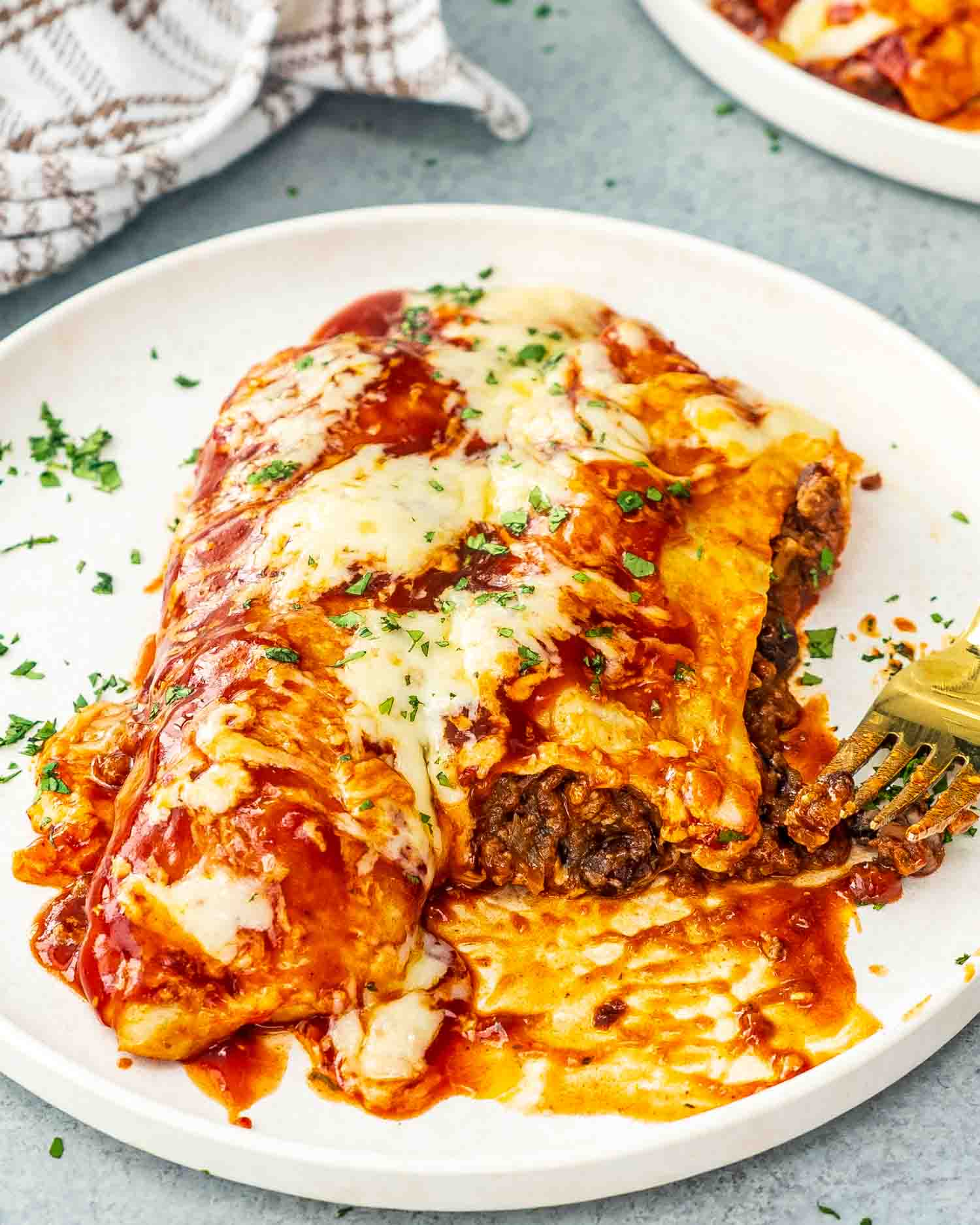 two beef enchiladas on a white plate garnished with cilantro.