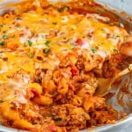 beefaroni topped with cheese and garnished with parsley in a skillet.