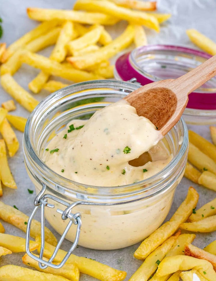 roasted garlic aioli in a jar with a wooden spoon in it.