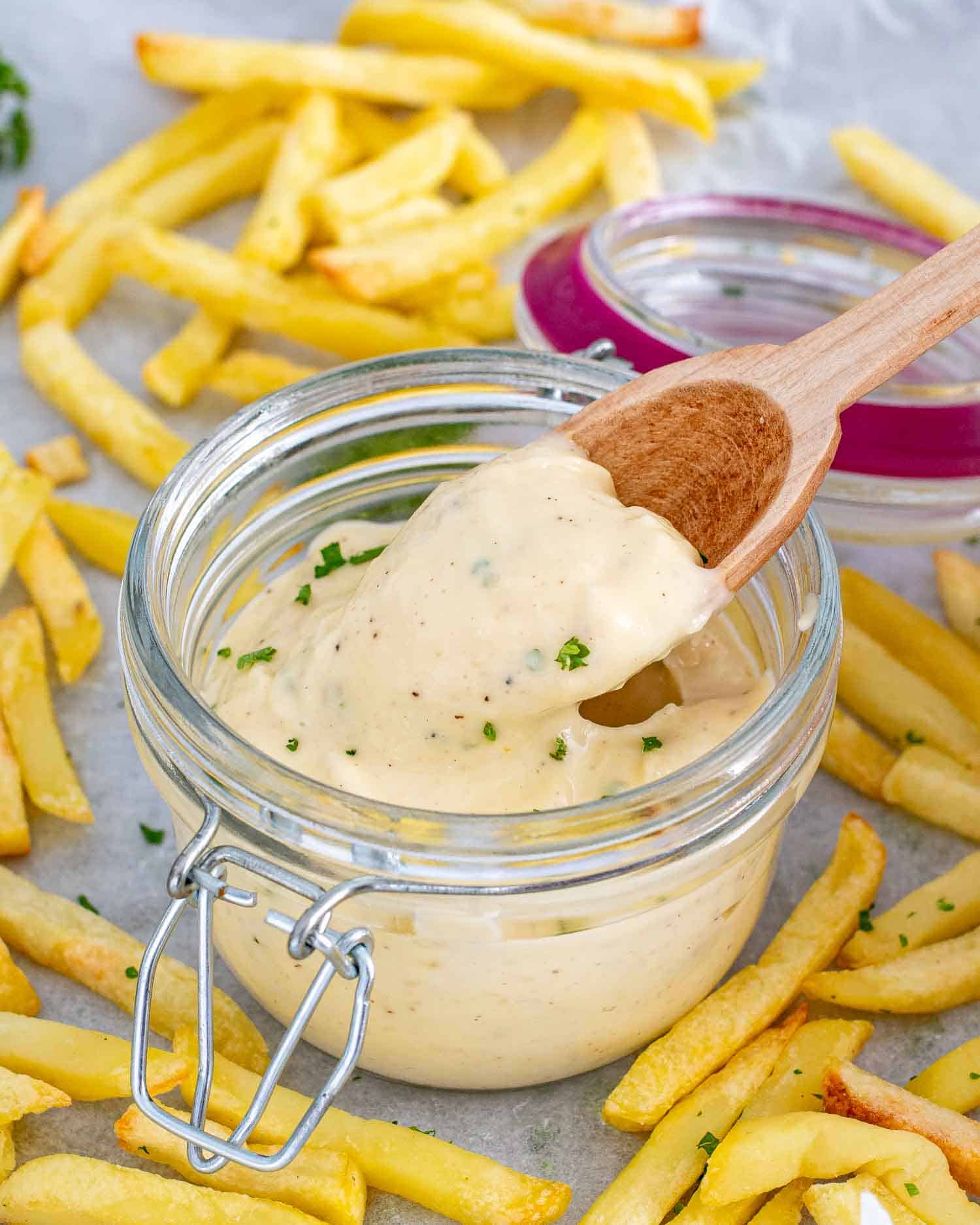 roasted garlic aioli in a jar with a wooden spoon in it.