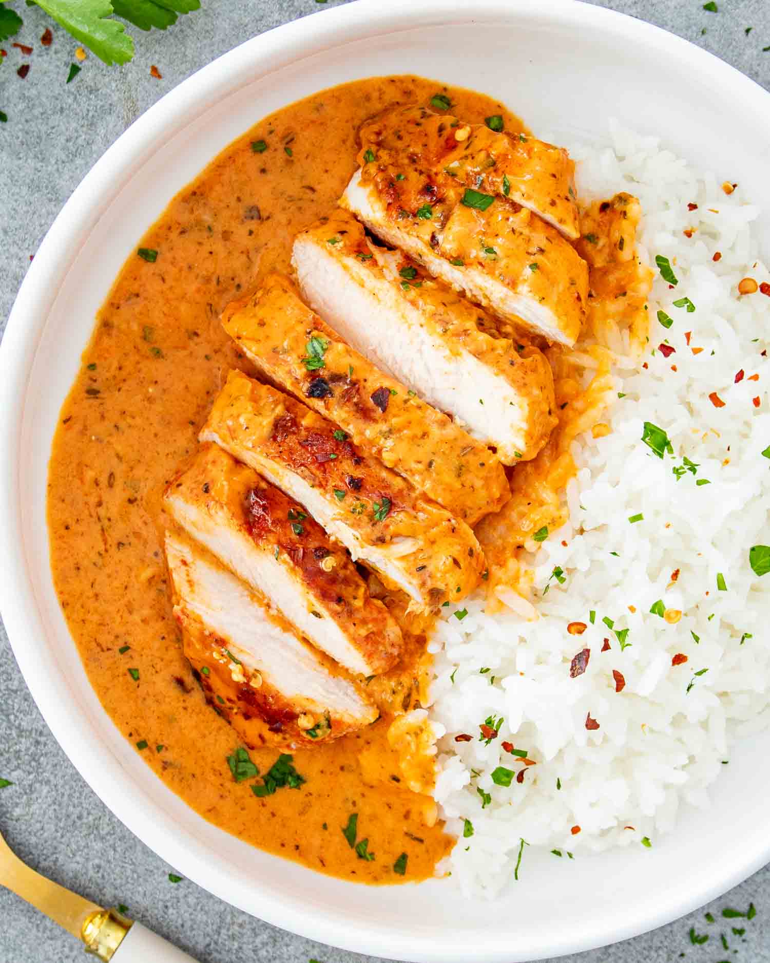 a roasted red pepper chicken breast with rice in a white plate.